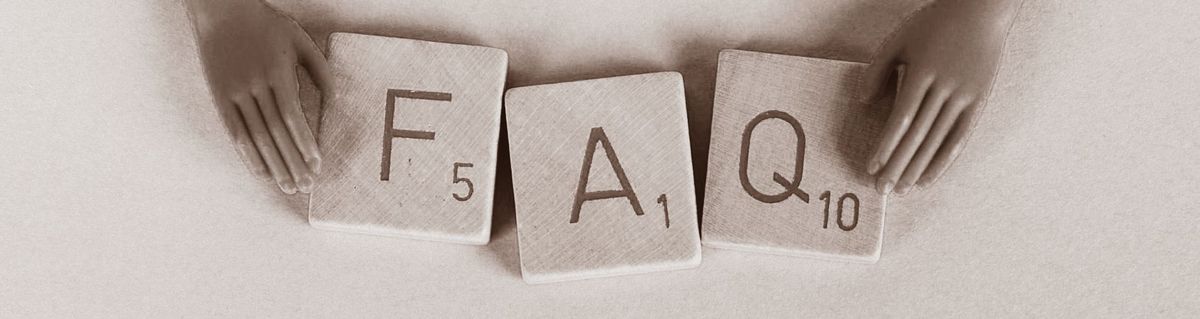 Hands arranging large Scrabble-style letter blocks showing F, A, Q — sepia tone