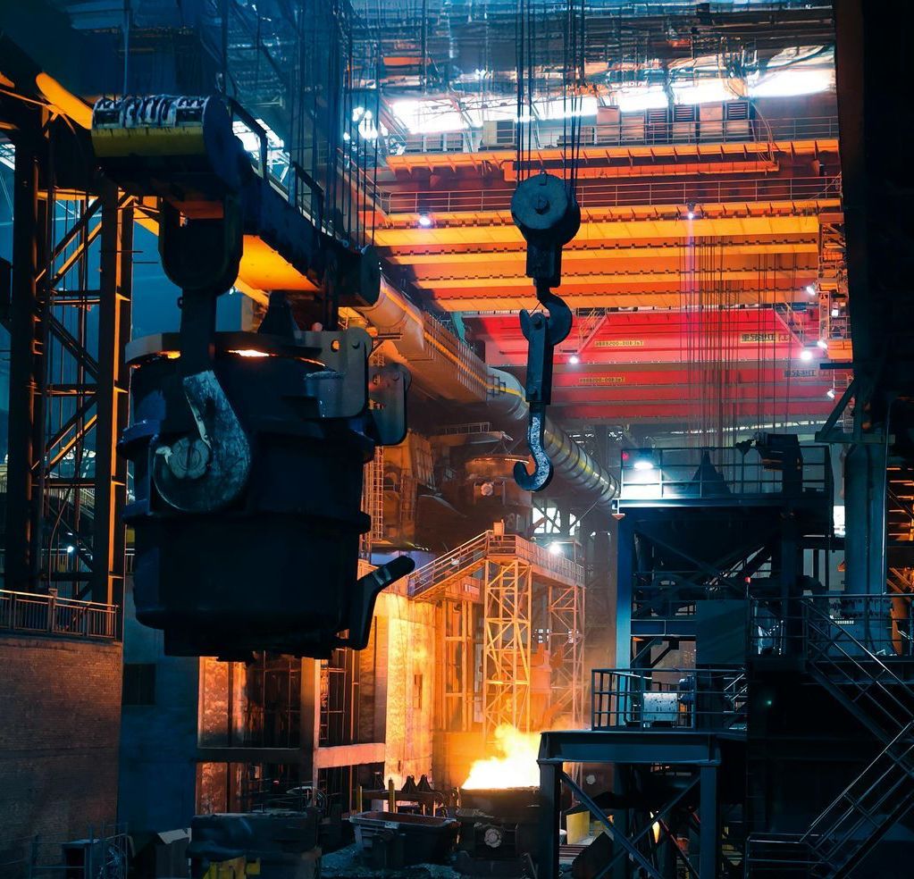 Steel mill / foundry interior — crane hook and ladle, molten orange glow below