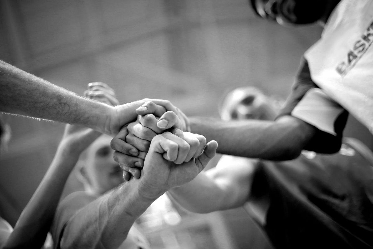 Team hands stacked together close-up, black-and-white