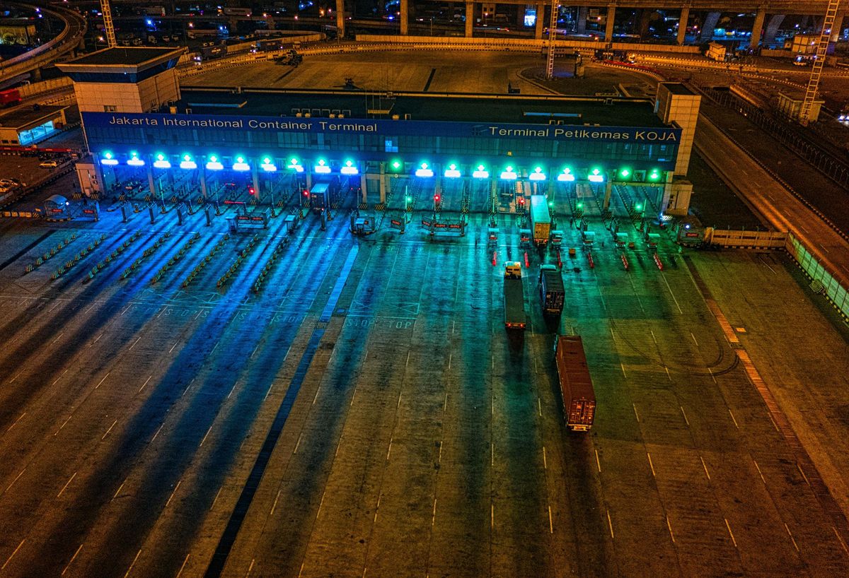 Container port terminal at night — lit gantries, trucks and yard, colour
