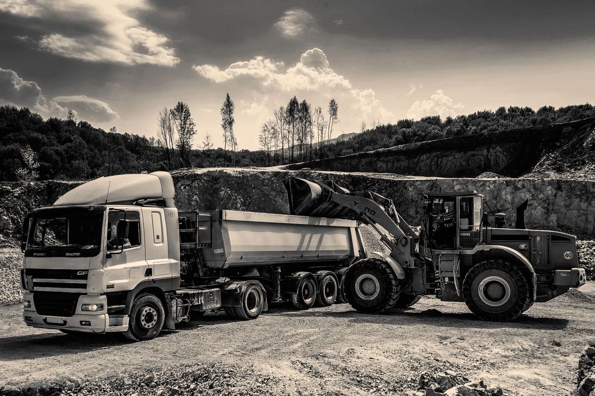 Truck being loaded at a quarry, hills and trees in the background, sepia tone — Value-Added Services
